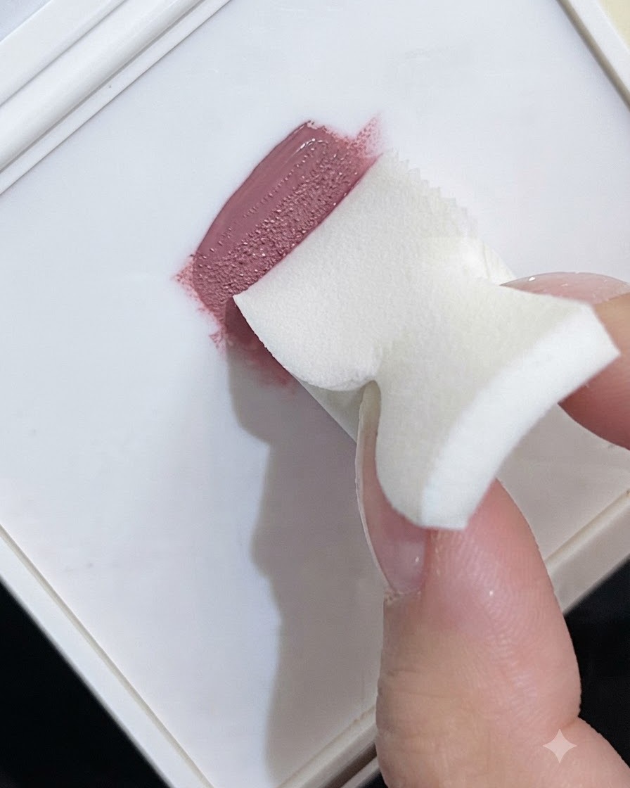 白いパレット上でピンクのジェルポリッシュを取り込み、グラデーションテクスチャを作っているフォームメイクスポンジ。