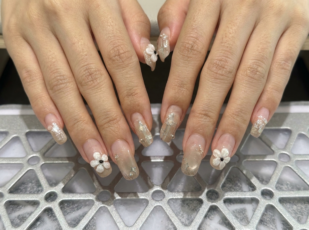 左手の指先に焦点を当て、美しいスクエアのフォルムと繊細なパールアクセントが施された様子を捉えたマクロ写真。