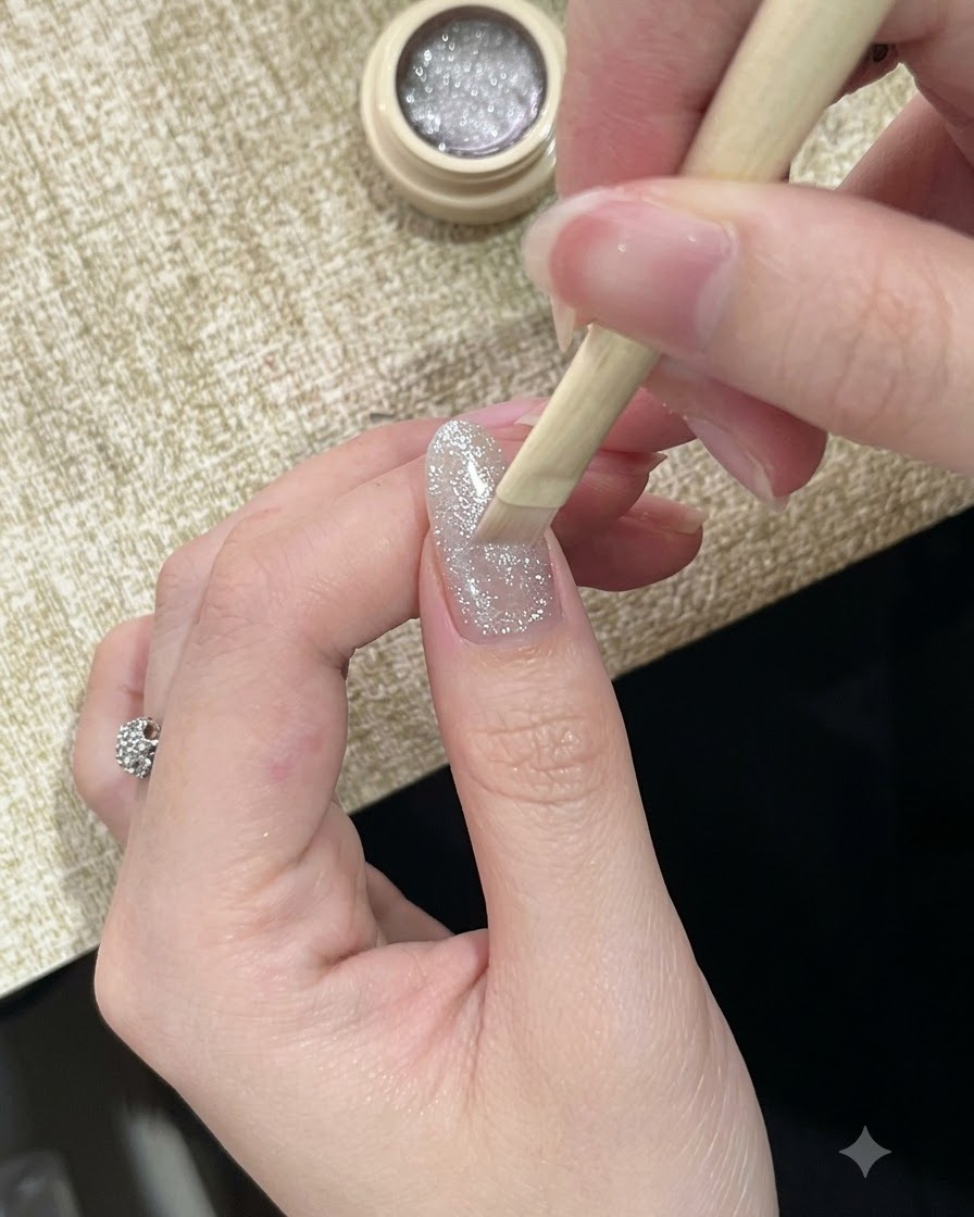 高輝度でキラキラしたシルバーのキャッツアイジェルポリッシュを爪にブラシで塗布している様子。