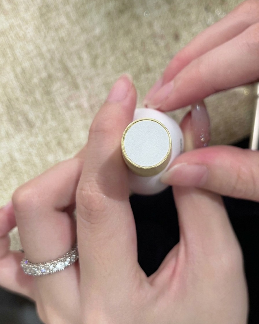仕上げのネイルアートを密封する準備ができている、クリアなトップコートのボトルを手に持っている様子。