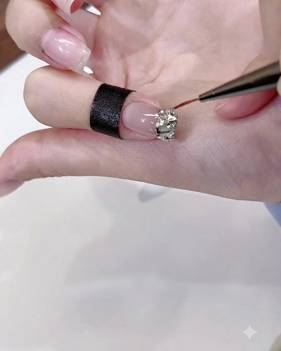 細いライナーブラシを使って、爪にのせたストーンの周りや隙間にクリアのダイヤモンドグルーを丁寧に塗っている様子。