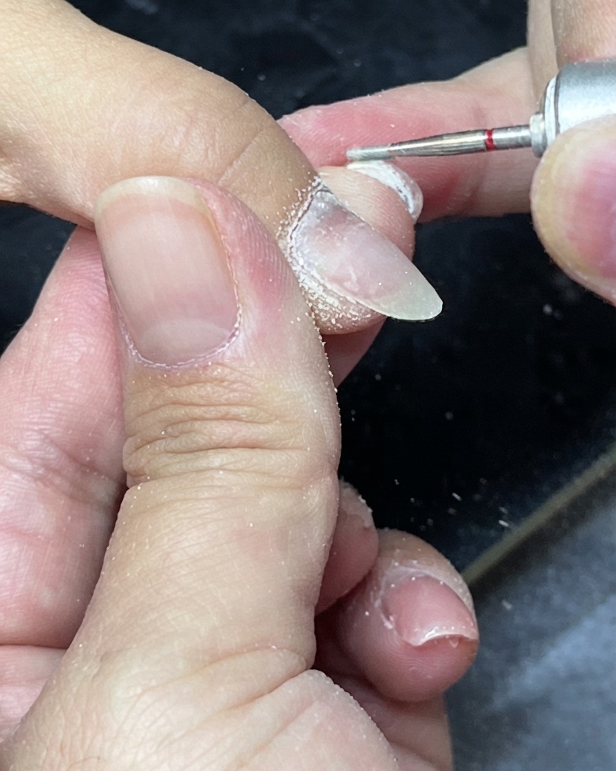 キューティクルニッパーを使い、爪の周りの余分なルーズスキンを丁寧にカットしている様子。