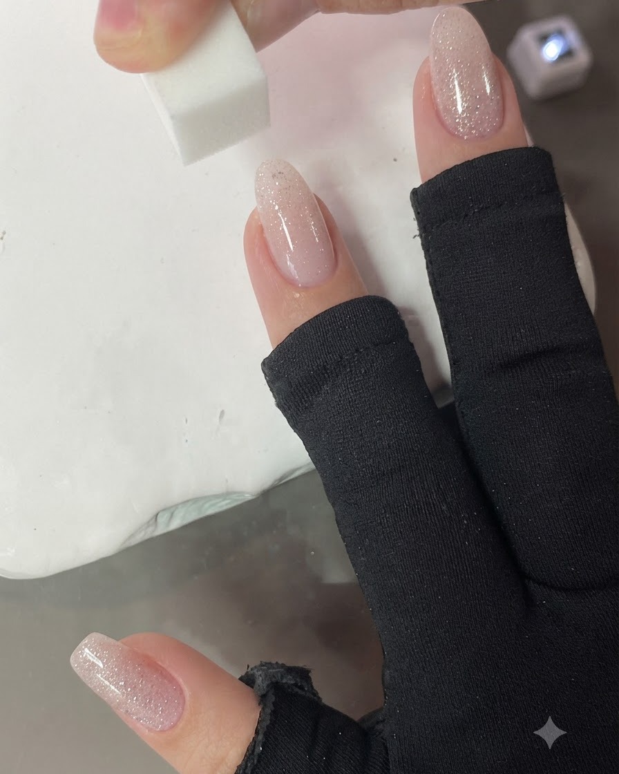 小さめのスポンジを爪に垂直にポンポンと当て、ヌードピンクのグラデーションをぼかしている様子。