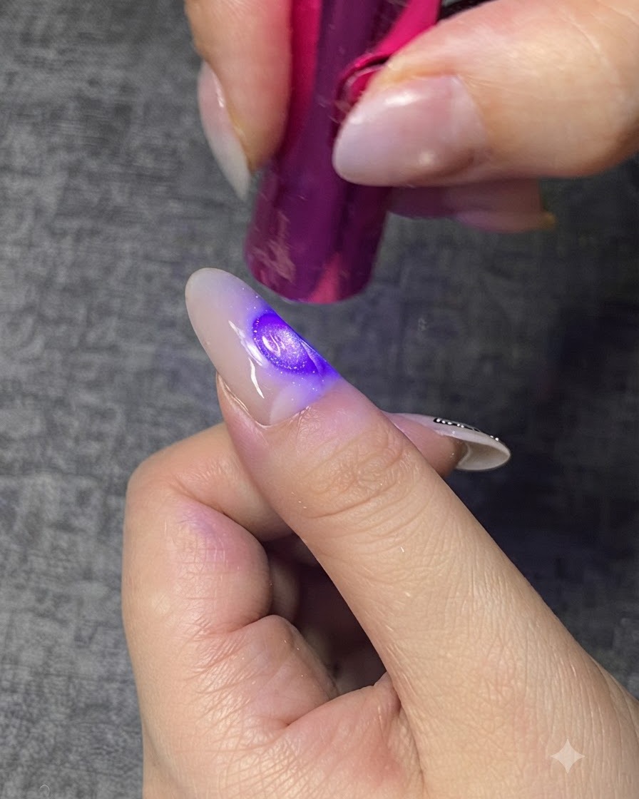 紫色のミニUV/LEDランプで、爪の上のクリアジェル層を硬化させている様子。