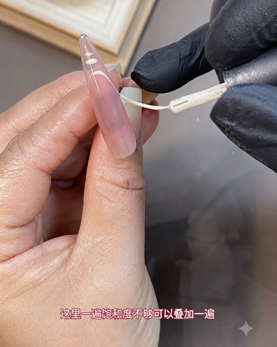 長い爪のフレンチチップ部分に、細いライナーブラシで白いジェルの2層目を重ねている様子。