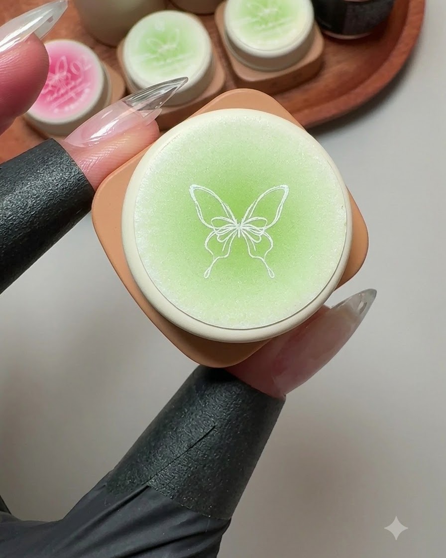 蓋に蝶のイラストが描かれたソリッドジェルの容器の周囲に、緑とピンクのジェルポットが置かれている様子。
