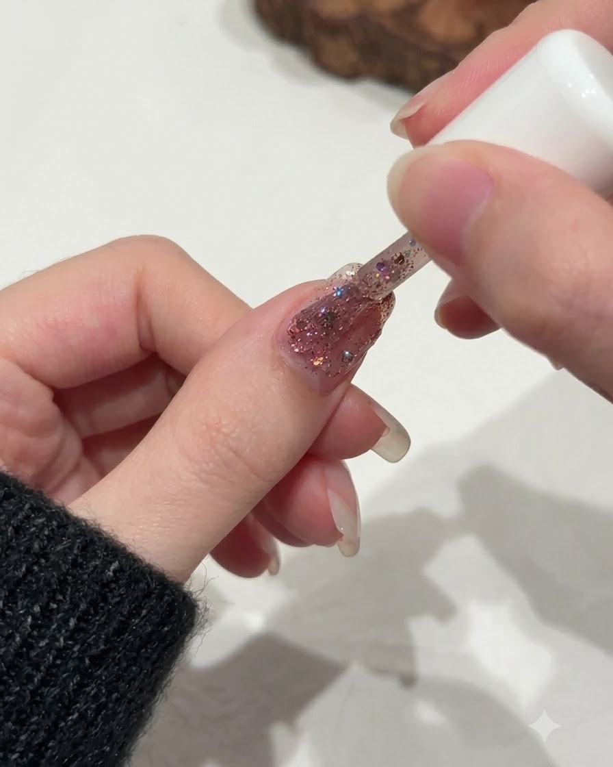 爪のキューティクルライン付近のグリッターの分布をブラシで繊細に整えている様子。