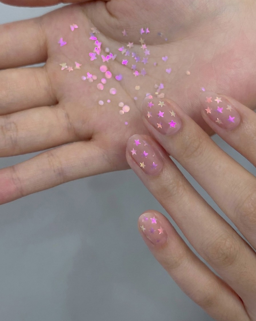 マニキュアブラシを使って、自爪にシアーなヌードジェルポリッシュの薄いレイヤーを塗布している様子