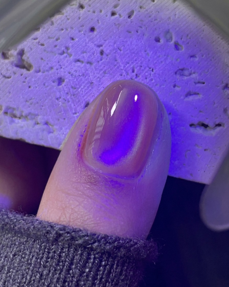 紫色のUV/LEDミニランプの下で硬化されている爪。
