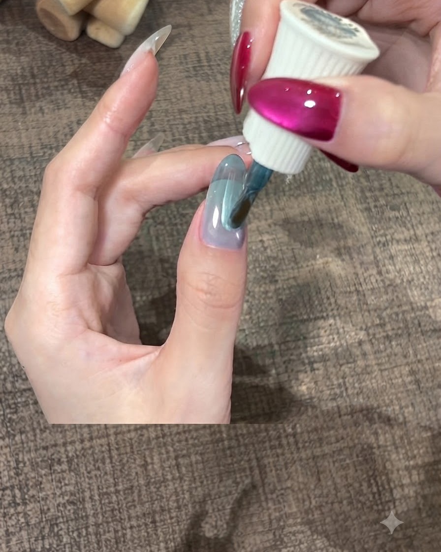 親指の爪の上にティールジェルポリッシュの厚い層を滑らかに広げているブラシ。