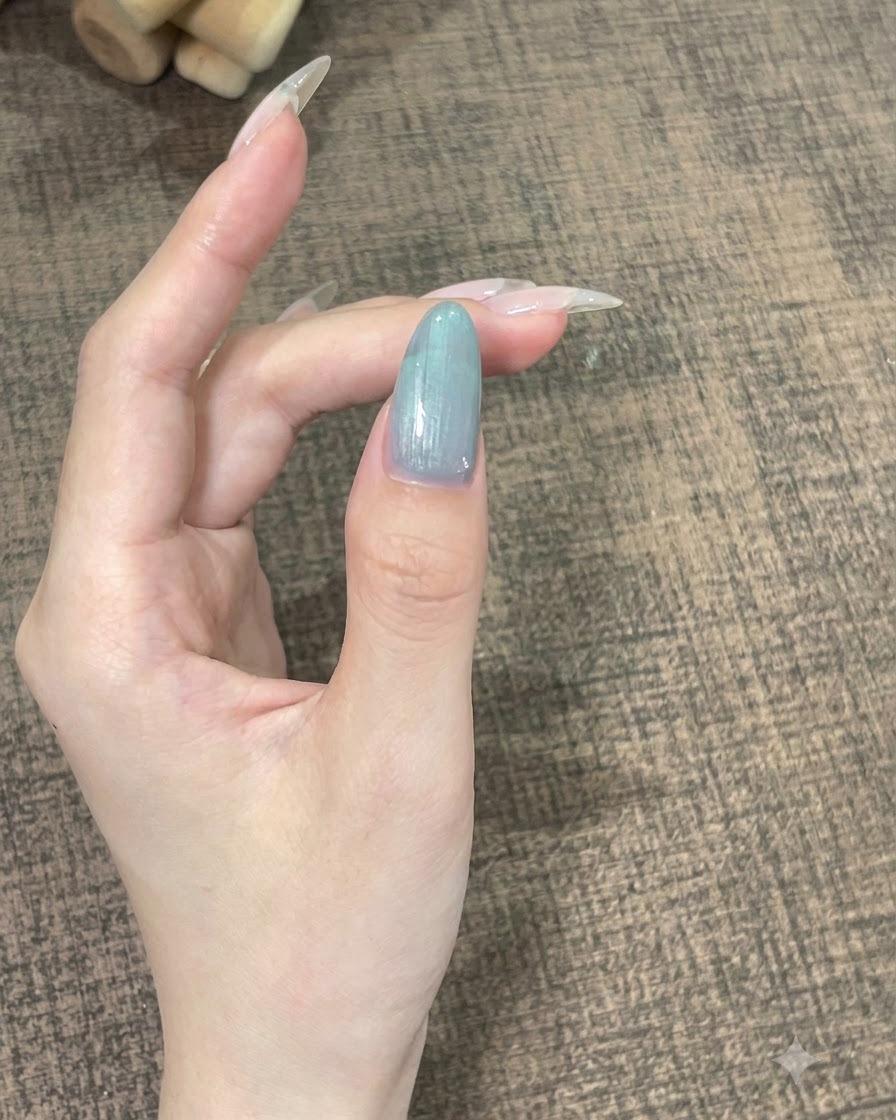 滑らかな曲線に落ち着かせるためにじっと保持されている、セルフレベリングジェルがついた1本の指のクローズアップ。