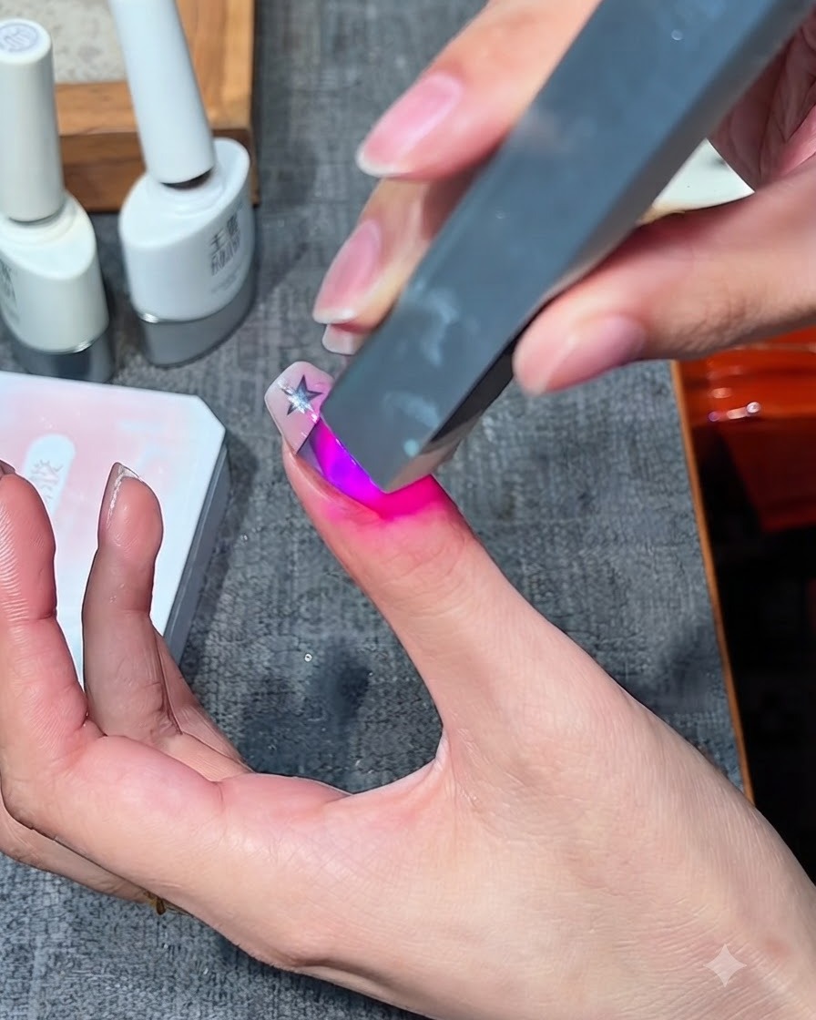 指の上のジェルデザインを硬化させているポータブルなミニUV/LEDネイルランプ。