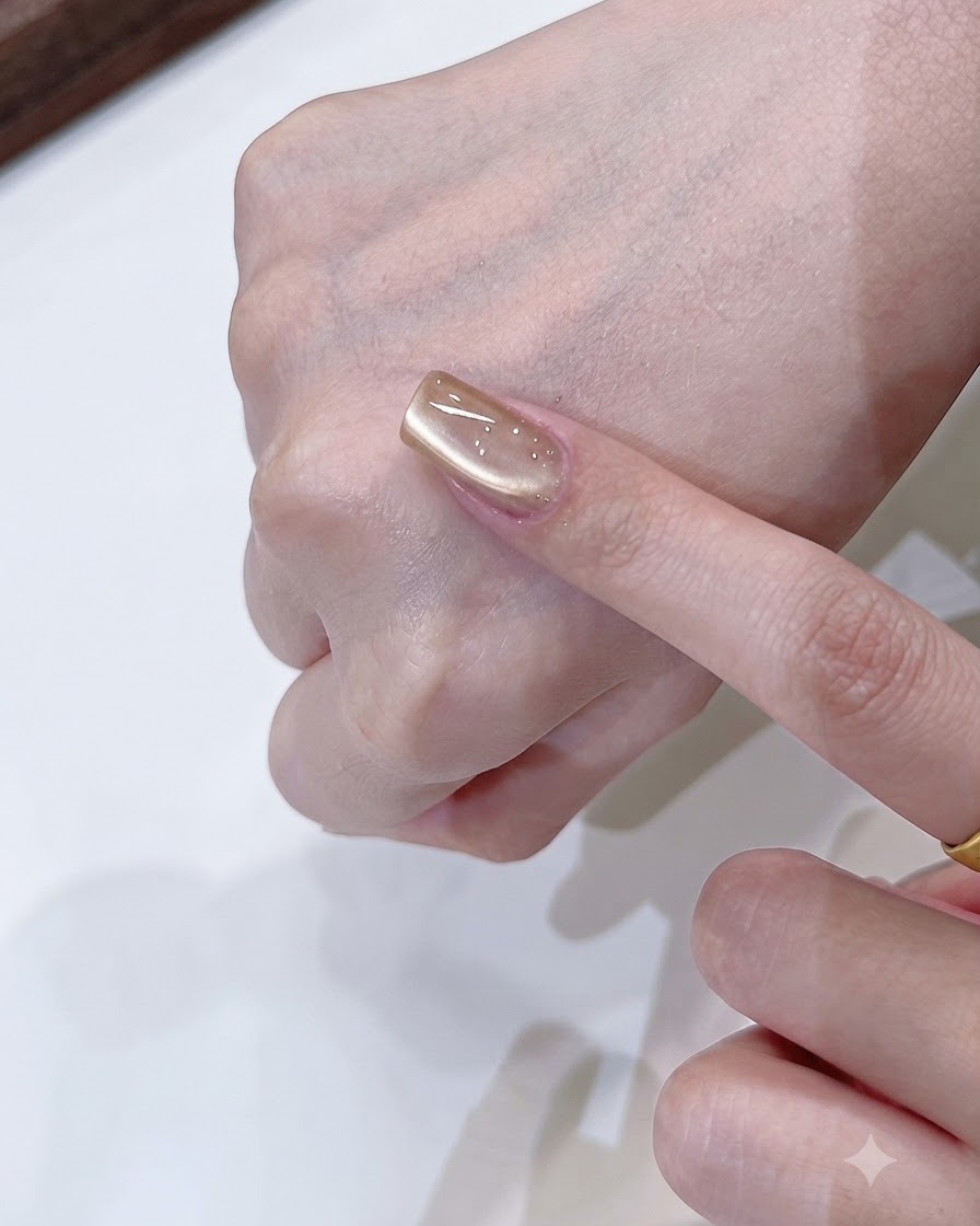 シャンパンゴールドのキャッツアイネイル上で、マグネットツールがソフトな片側の光の反射を形作っている様子。