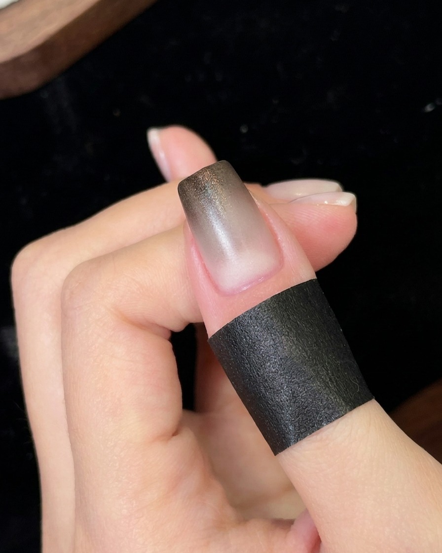 新しく塗布された黒のグラデーション層を、小型のポータブルUV/LEDライトの下で硬化させている爪。