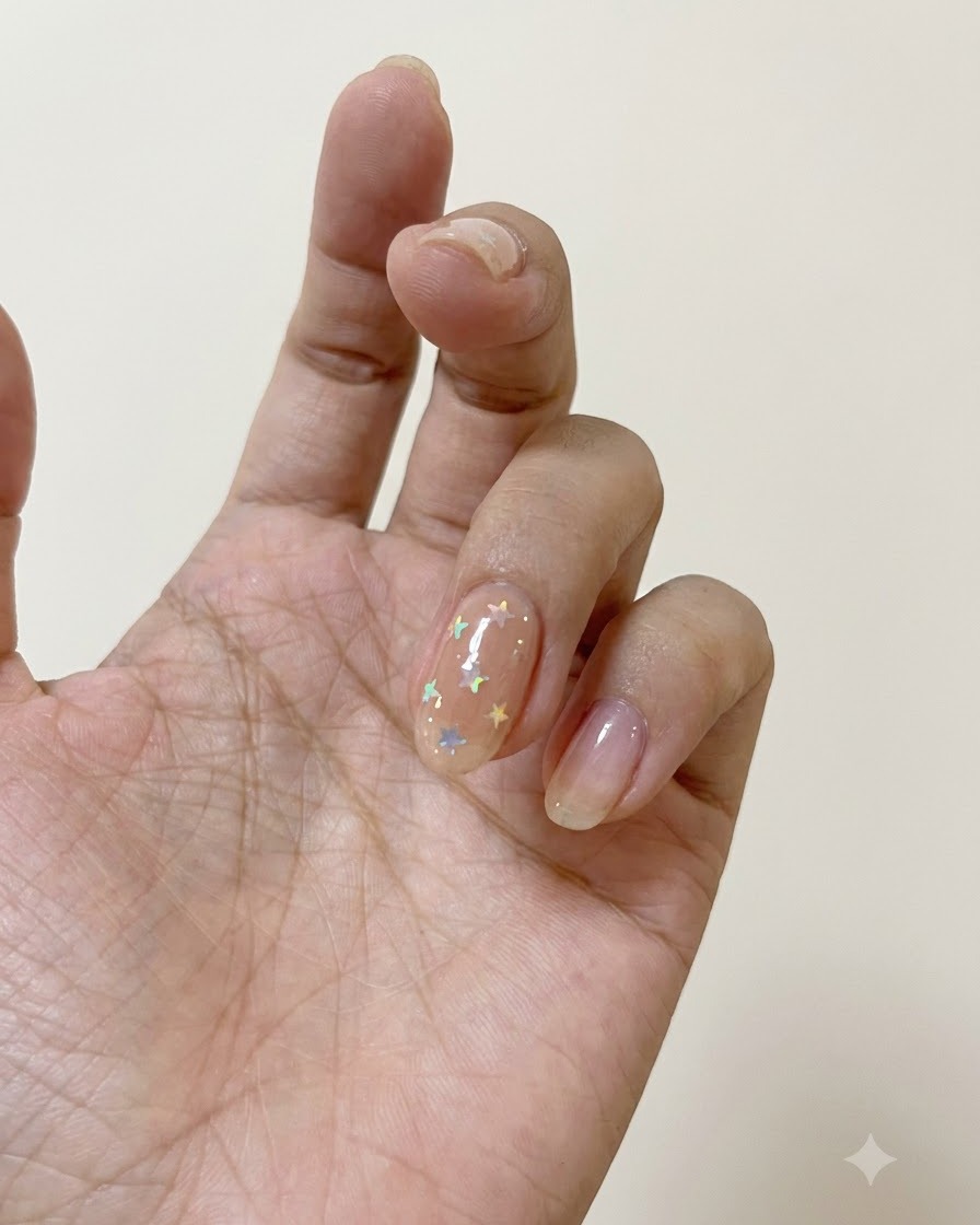 偏光スターで飾られたネイルの上に、ネイルブラシでマットトップコートを塗布している様子。