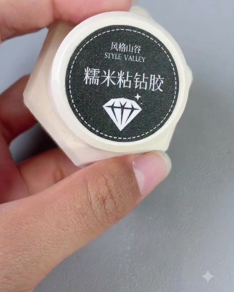 ネイルブラシの隣で、Style Valleyのスティッキーダイヤモンドジェルの小さな容器を手に持っているところ。