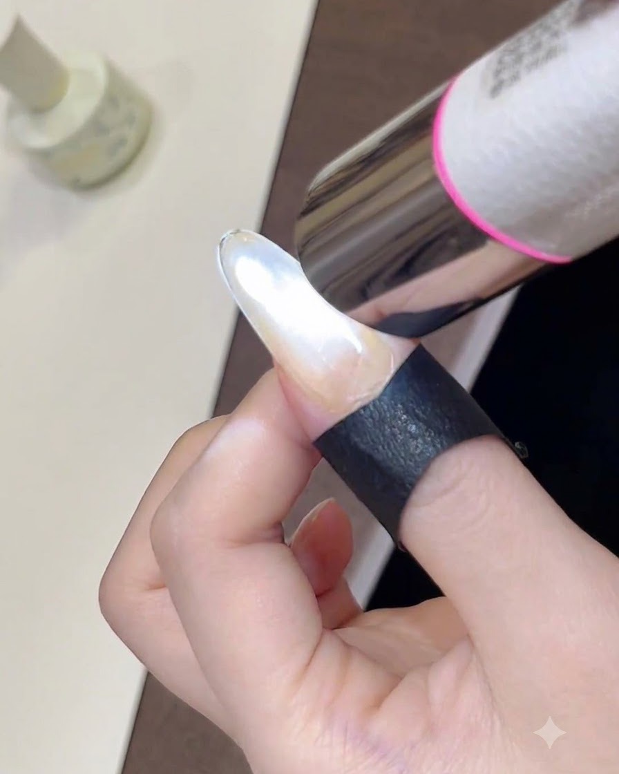 ハンディタイプのミニUVライトを使い、スタイリングしたての輝くキャッツアイジェルポリッシュを硬化させているクローズアップ画像。
