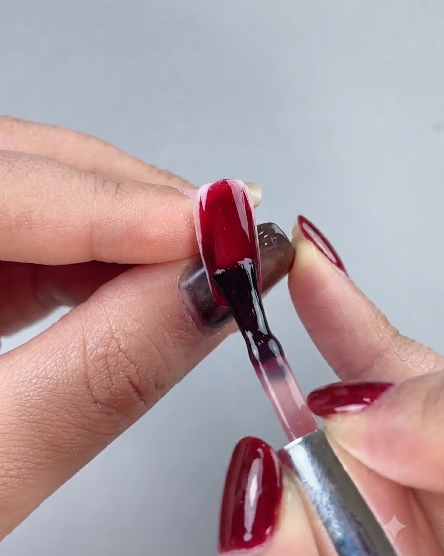 ロングのネイルチップ全体に深みのあるオックスブラッドレッドのカラージェルを塗布しているネイルブラシ。