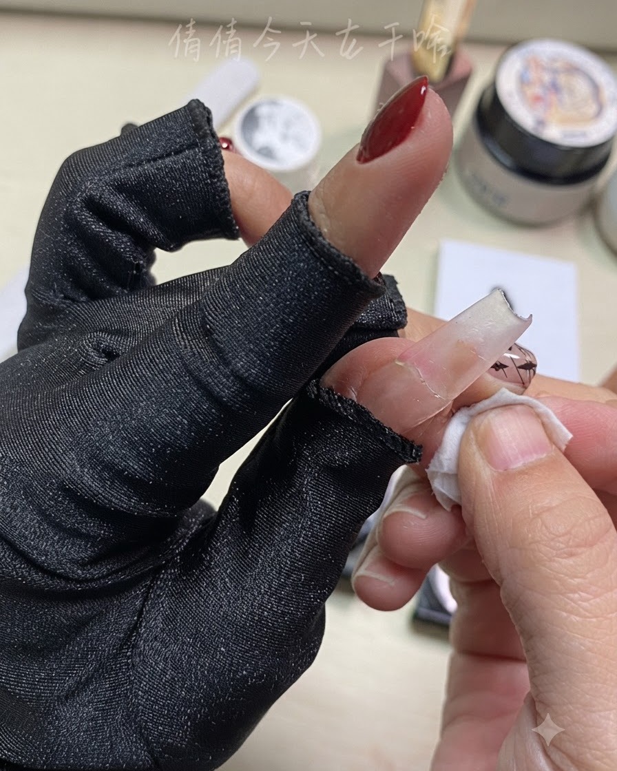 完成したネイルアートの近くで、コットンを使って指を拭いている手元のアップ。