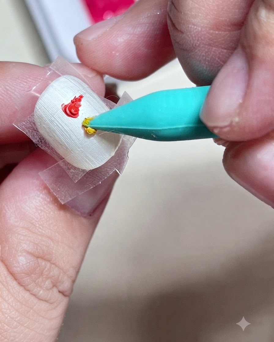 精密なシリコンネイルツールを使って、爪のテープ内の赤いドットのすぐ下に黄色いジェルペイントのドロップを乗せているクローズアップ。