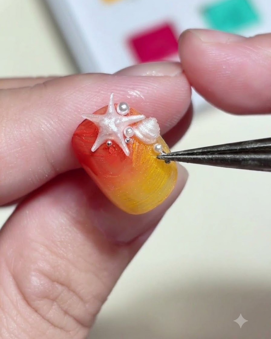 ピンセットを使い、爪の上の3Dヒトデパーツの周囲に極小の白いパールビーズとメタリックスタッドを配置している様子。
