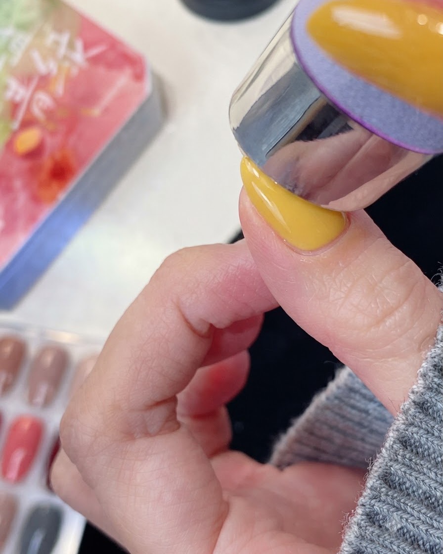 ネイルデザインを施した指をUV/LEDネイルライトに入れて硬化している様子。