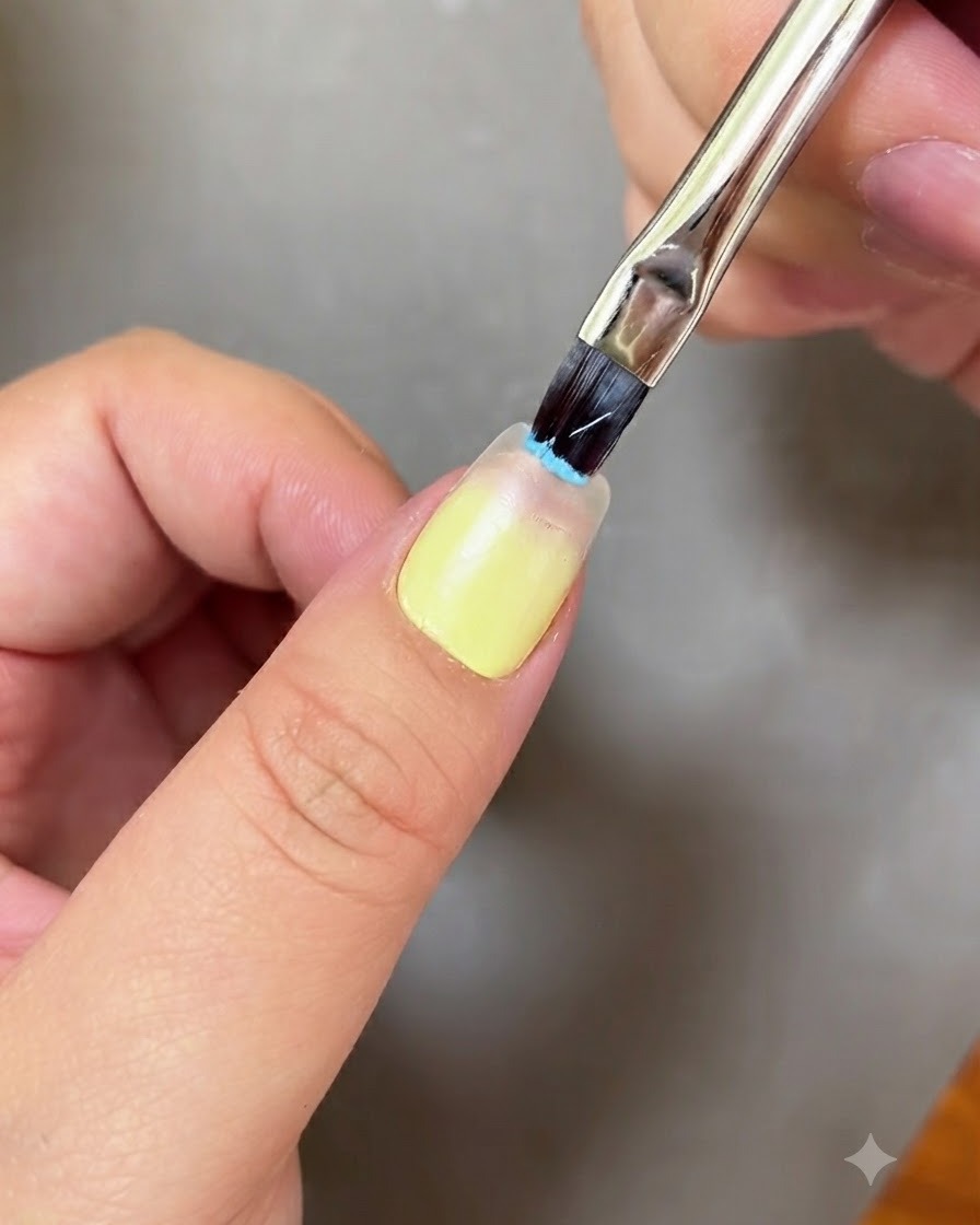 ネイルブラシで爪先にライトブルージェルを塗布している様子。