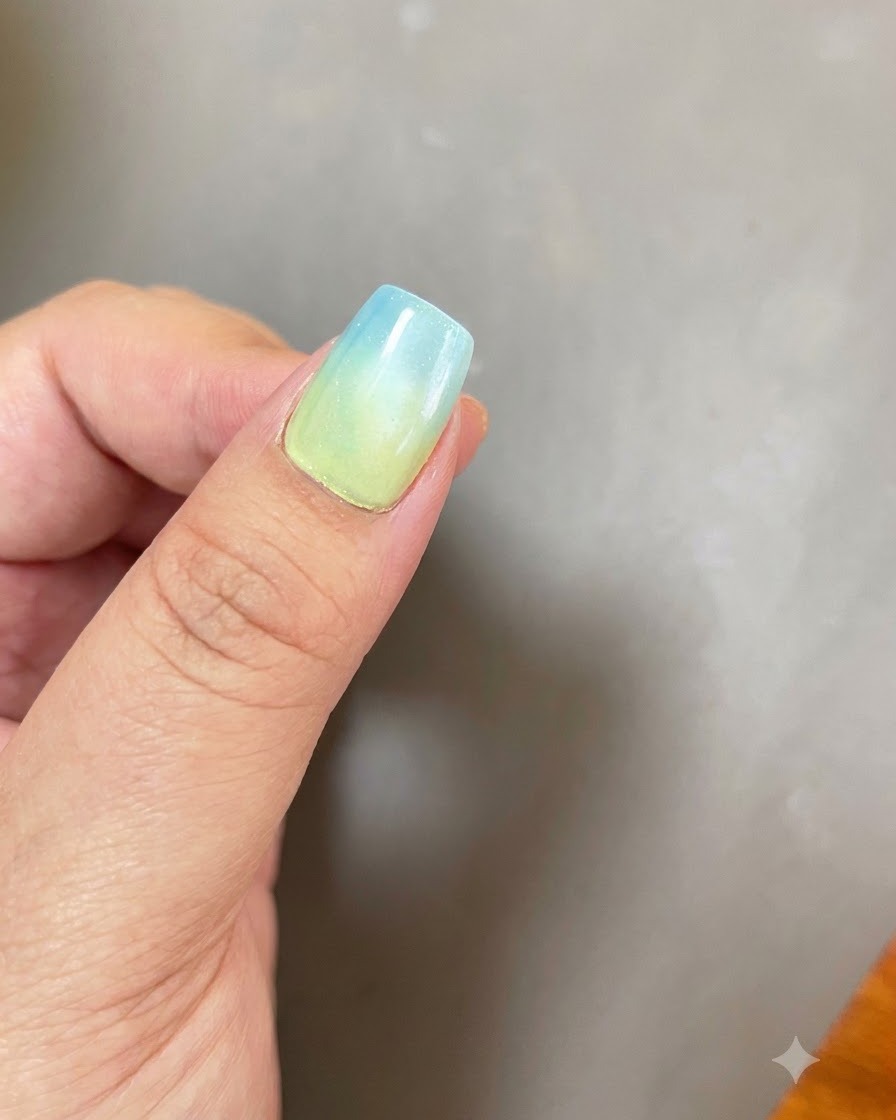 ブルーからイエローへのオンブレベースと円形のマグネットキャッツアイ効果を持つ爪を、紫色のUV/LED硬化ライトの下に置いている様子。