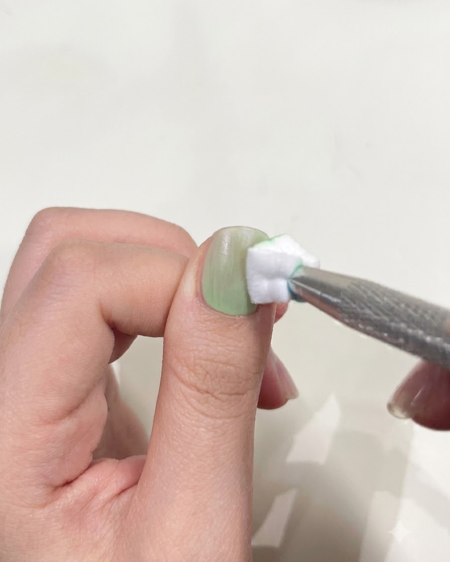 コンパクトなミニUV/LED懐中電灯の下に置かれてジェルポリッシュを硬化させている親指。