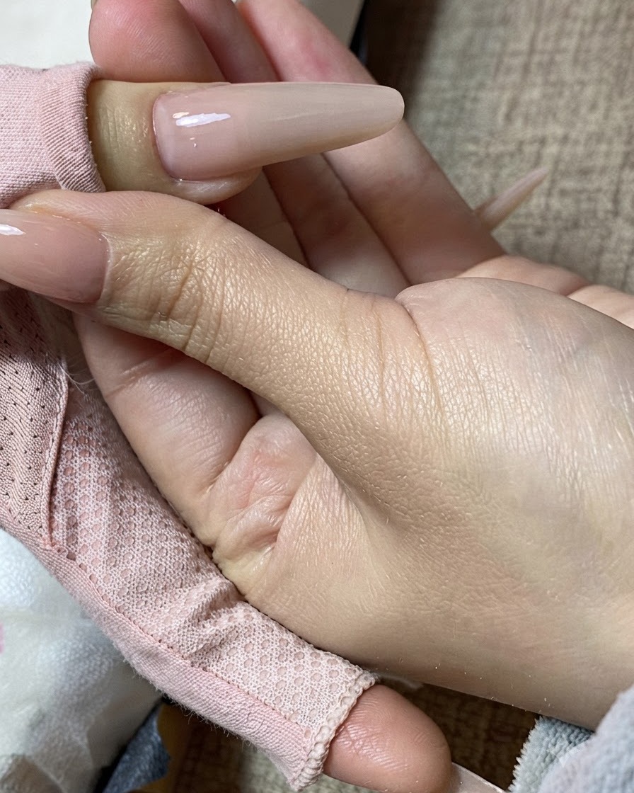 ミルクティーカラーに仕上げられた美しいネイルを持つ手のクローズアップ。