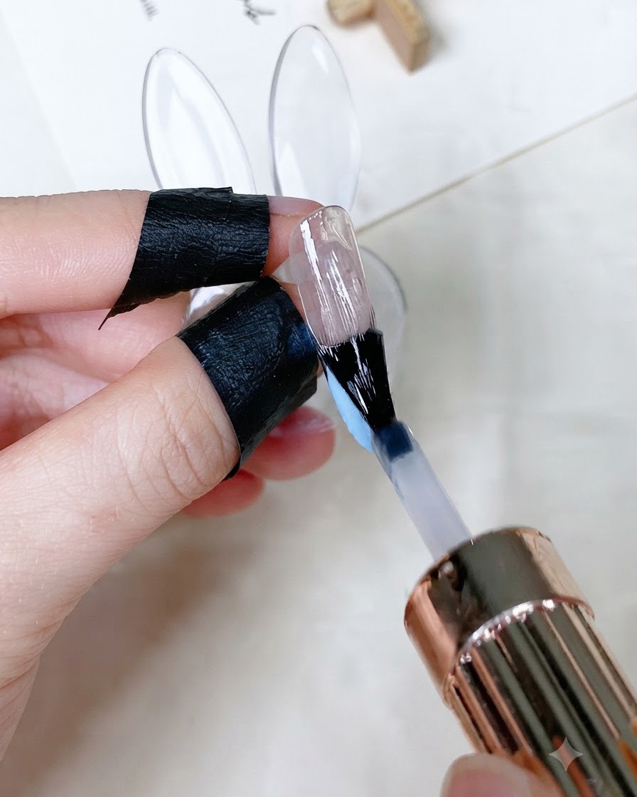 アートを施した爪全体に、クリアなツヤありトップコートをブラシで塗布している様子。
