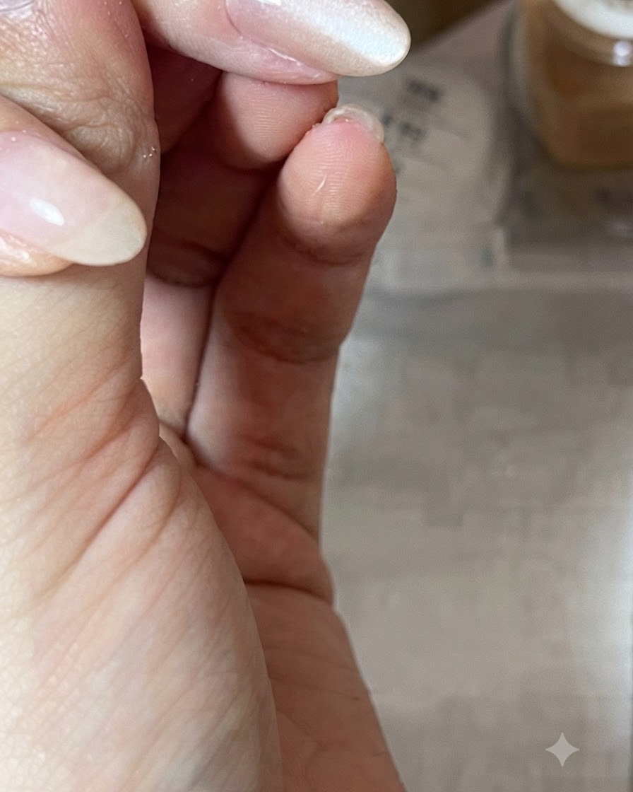 ツヤのあるヌーディーなジェルネイルの上に斜めにマグネットをかざし、キャッツアイの光をデザインしている手元のアップ。