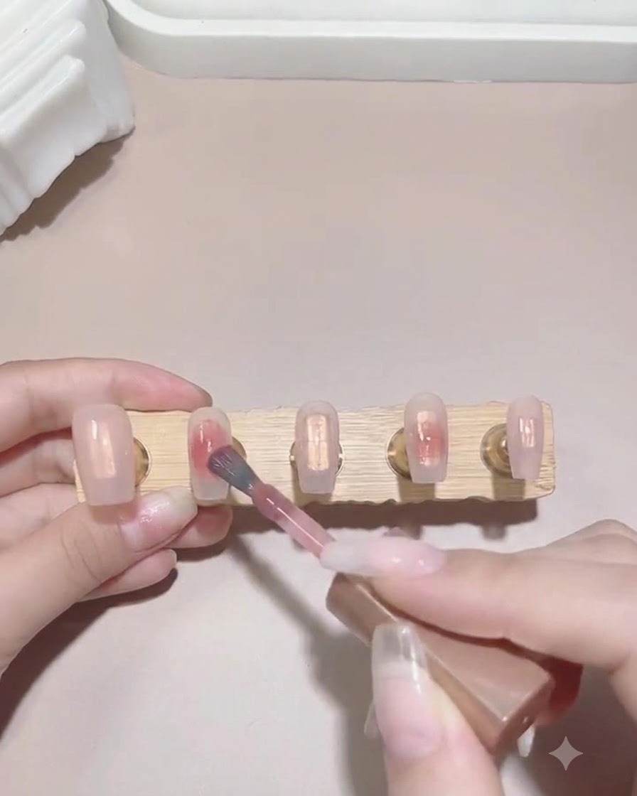 濡れたネイル表面にピンクのカラージェルを少量置き、グラデーションを作っている様子。