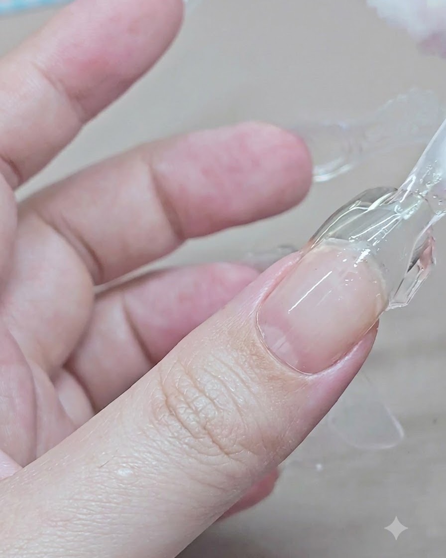 人差し指の硬化したクリアジェルの上からプラスチックフォームの両脇をつまんで外している様子。