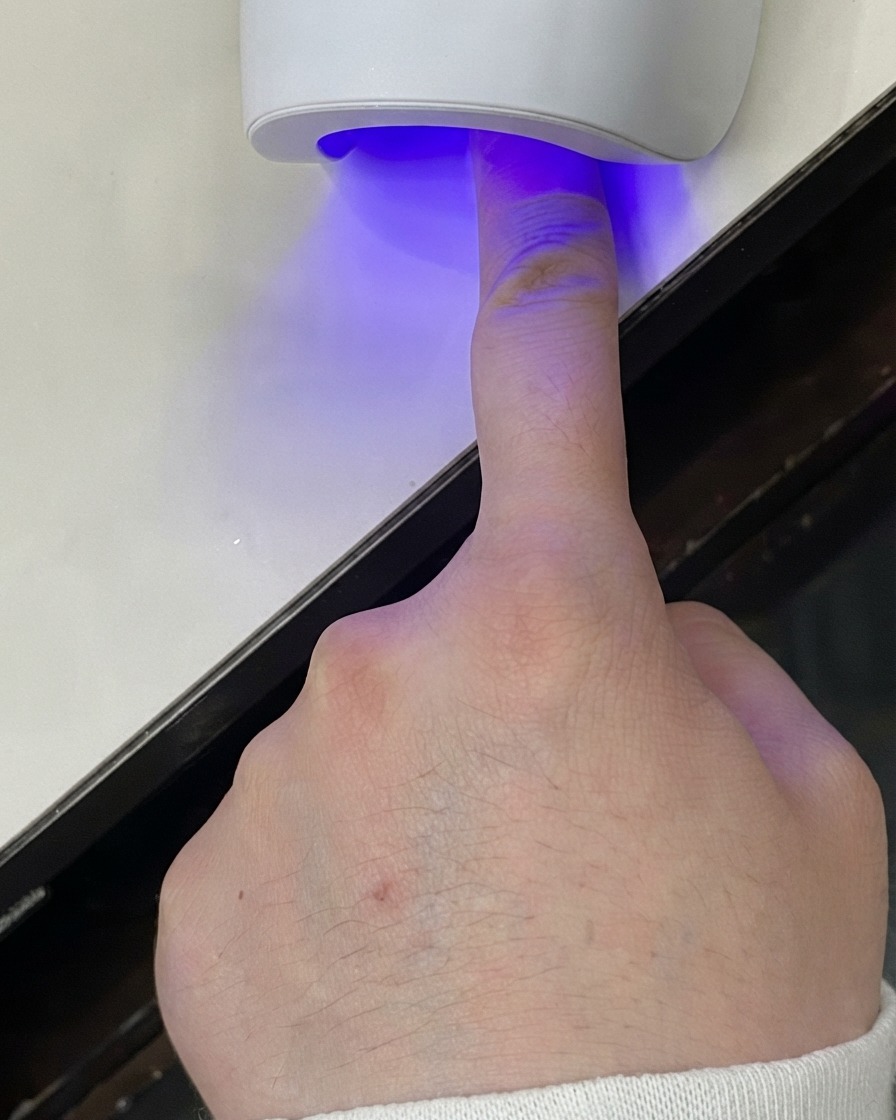 ミニUV LEDランプの下に置かれ、ジェル層が硬化されている指。