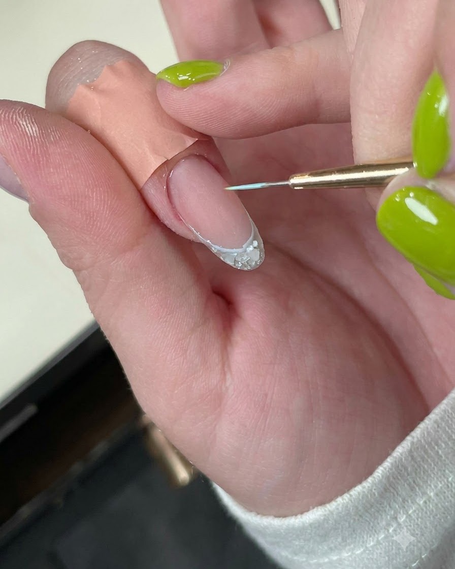 繊細なブルーのボーダーラインが描かれた爪が、ミニLED硬化ランプの下に置かれている様子。