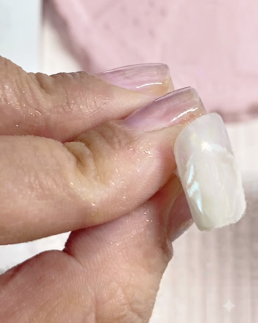糸くずの出ないワイプで、仕上がったネイルのエッジから余分なクロムパウダーをきれいに拭き取っているところ。
