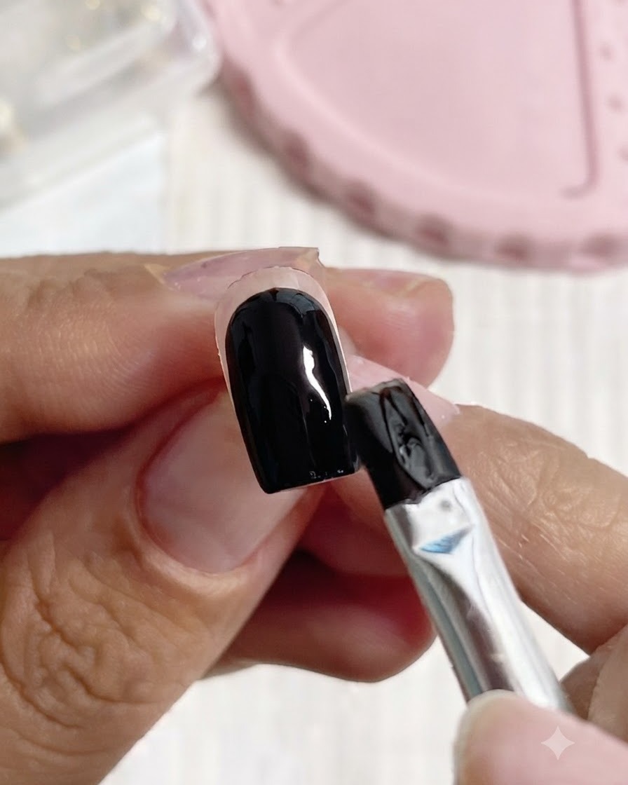 ブラシが黒と白のネイルベースの上にクリアビルダージェルを塗布しているところ。