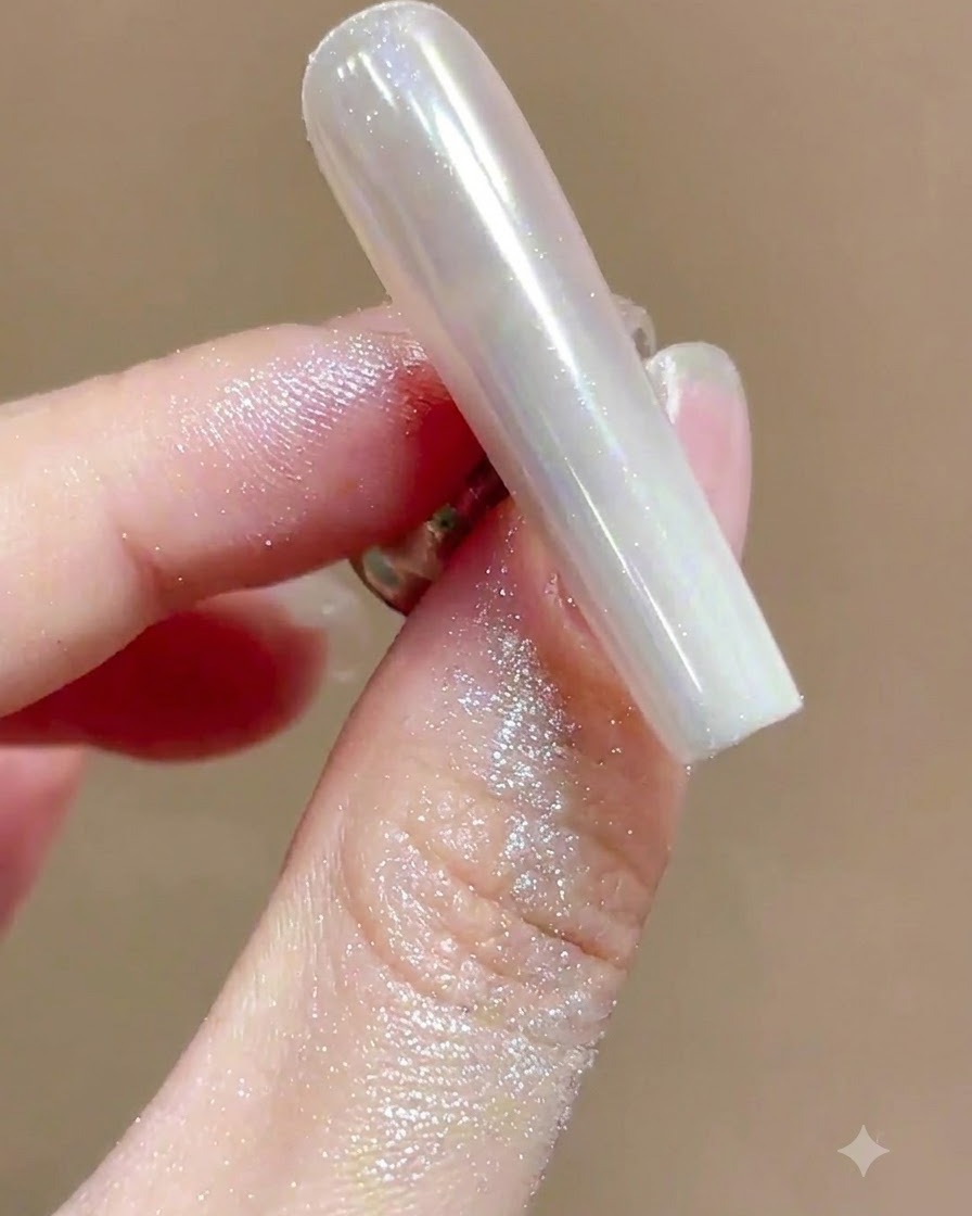ソフトなブラシがハイグロスなクロームマニキュアネイルから余分なしみわたるパウダーを掃き出している様子。