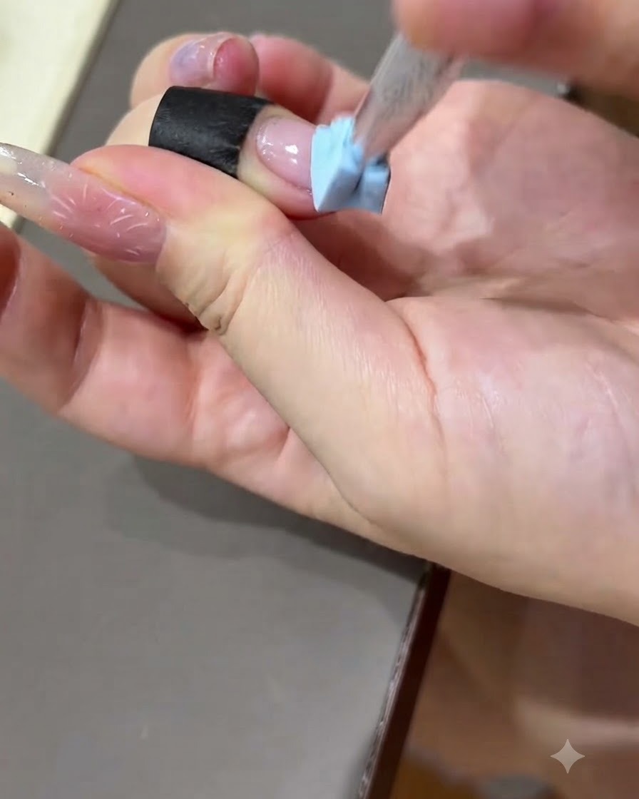 練習用ネイルプレートの表面に手でブラックの練習用ストリップを押し付けている様子。