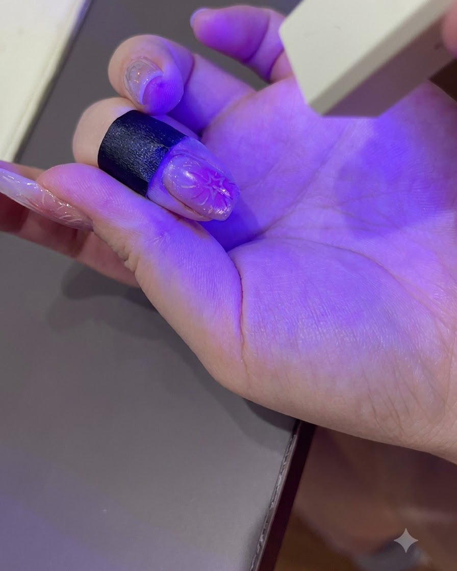 ポータブルなUV/LEDネイルランプの紫色の光の下で硬化しているマニキュアを施した手。