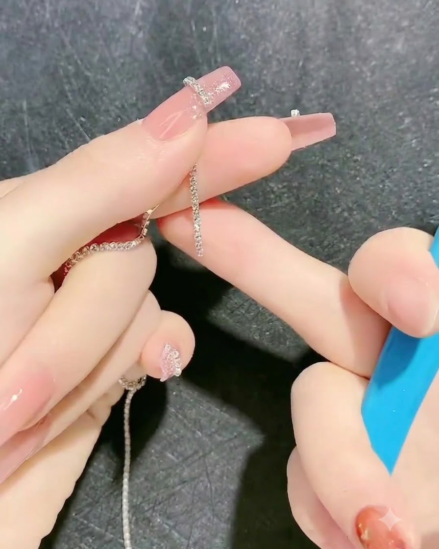 ツールを使って、未硬化のジェルで作ったハートの輪郭の上にラインストーンチェーンを慎重に置いている様子。