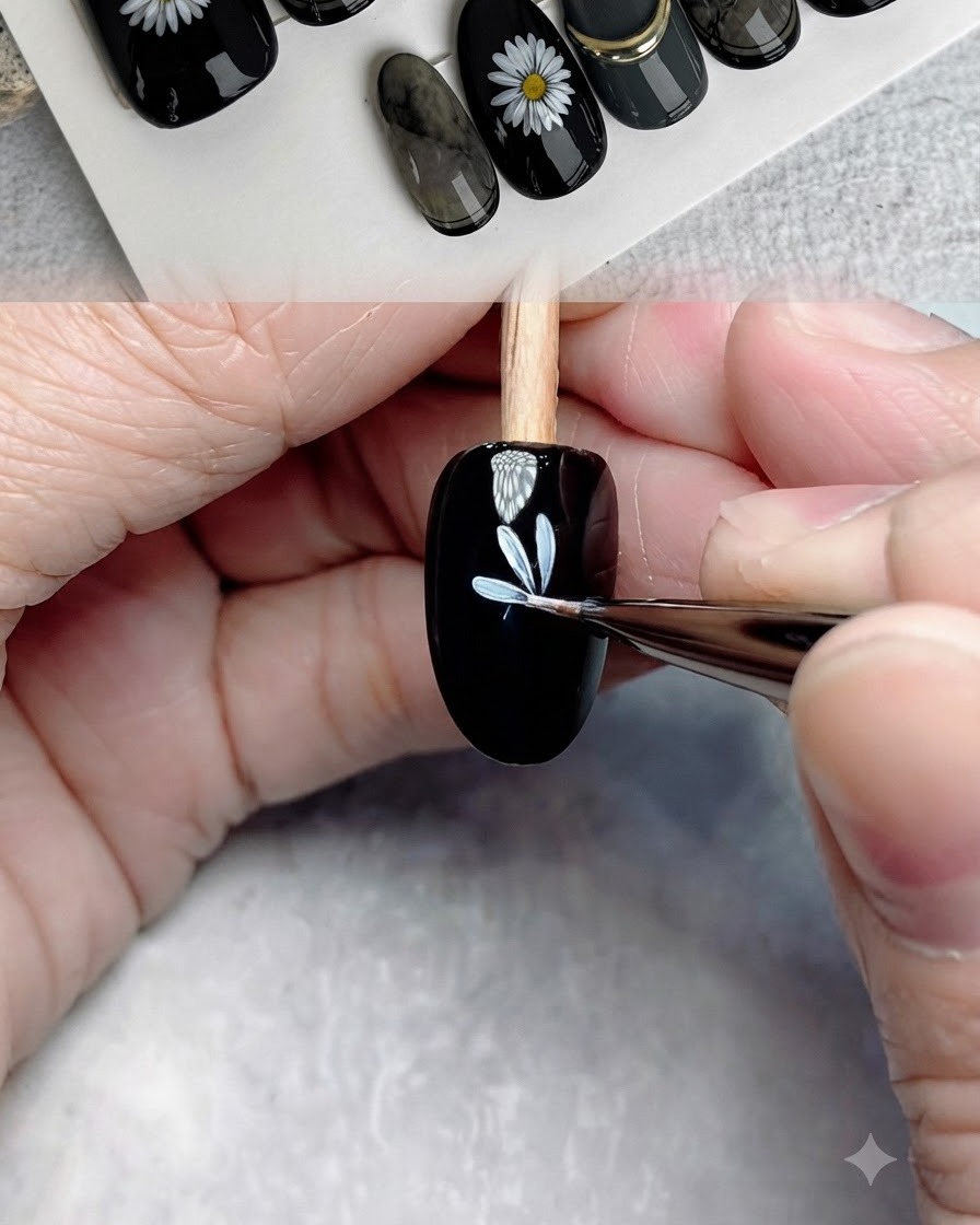 極細のディテールブラシを使って白い花びらをさらに描き加え、黒いネイル上の1層目の花を完成させている様子。