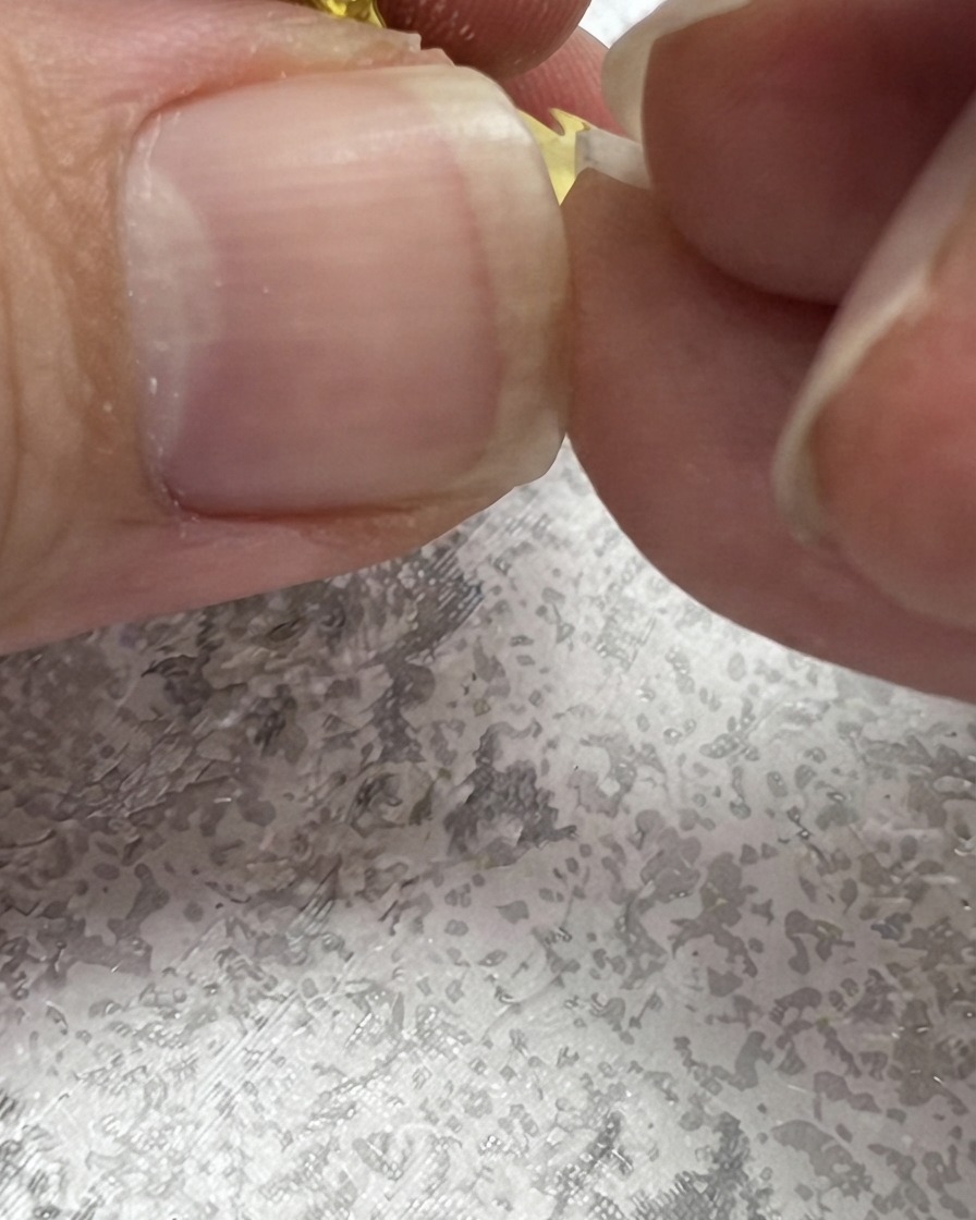 デイジーの横に葉の形を作るため、ネイルブラシが上向きに緑色のストロークを描いている様子。