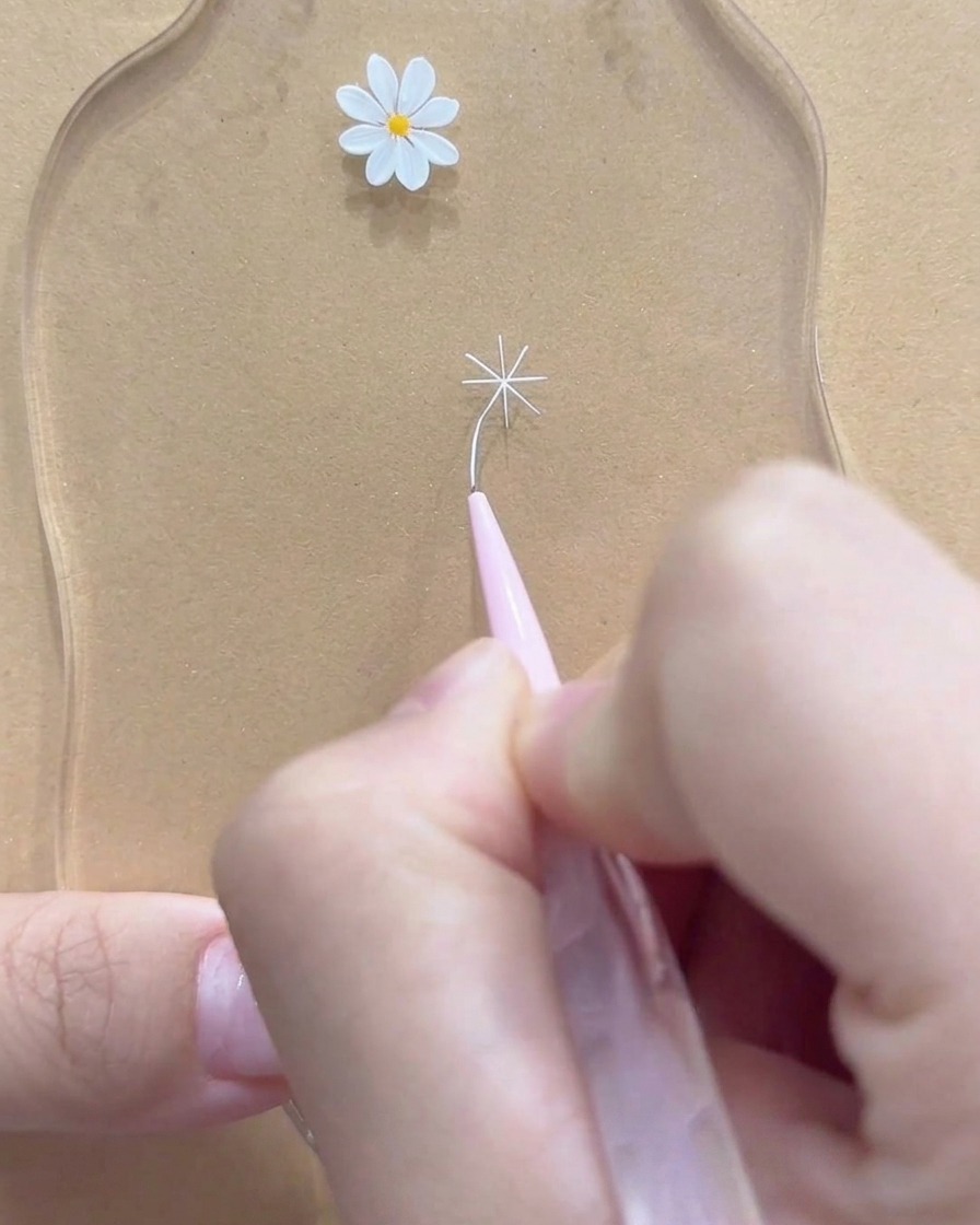 白いデイジーの花の外側の先端を完璧に整えている極細ライナーブラシのクローズアップ。