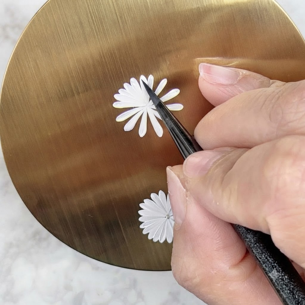 ネイルアートブラシがデイジーのデザイン上に2層目の小さめの白い花びらを慎重に描いている様子。