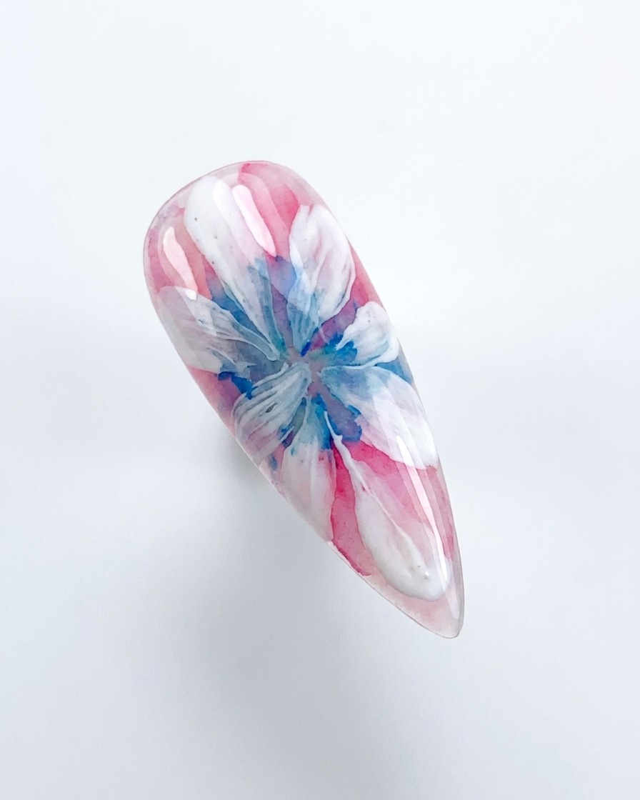 デコレーションされたネイルをピンク色のUV/LED硬化ランプの下に配置している手。