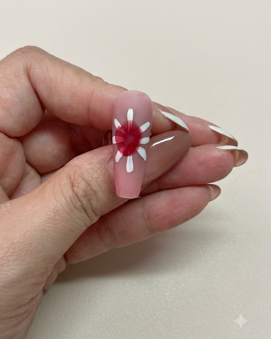 白い花びらに囲まれた、柔らかく拡散したレッドのブルーミングセンターを持つピンクのネイルのクローズアップビュー。
