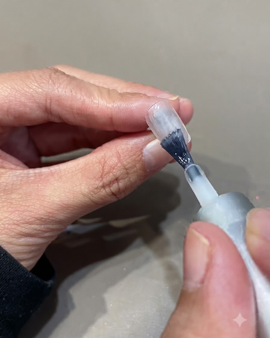 ネイルブラシを使って、自爪の表面に半透明のホワイトジェルポリッシュを2度塗りしている様子。