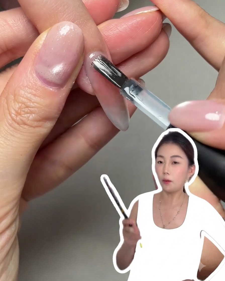 ネイルブラシを使って、整えられた爪の表面に透明なジェル層を滑らかに塗布している様子。